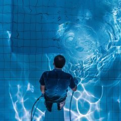 Pool maintenance, swimming pool cleaner, man in blue shirt with cleaning equipment, hotel service, water cleaning, generative ai illustration